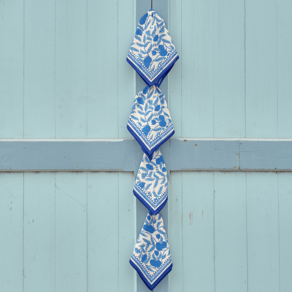 Blue and white patterned napkins hanging on a blue wooden door.
