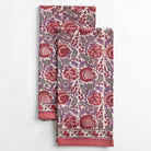 A set of two folded Bohemian floral dust rose tea towels with a printed floral pattern in pink, purple, and beige colors.