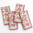 A set of folded cotton napkins with a ginkgo leaf pattern in coral hues