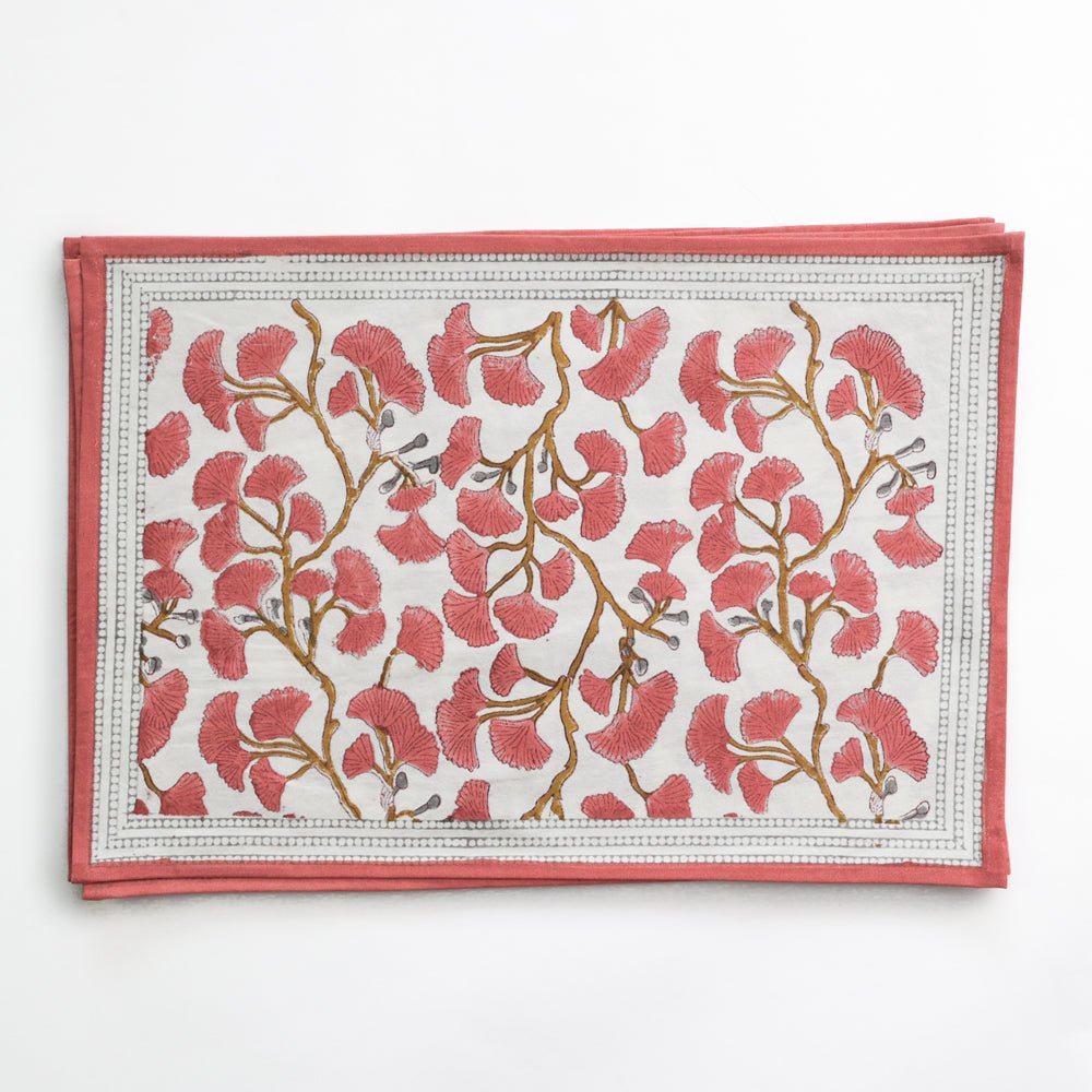 A set of placemats with a ginkgo leaf pattern in coral hues