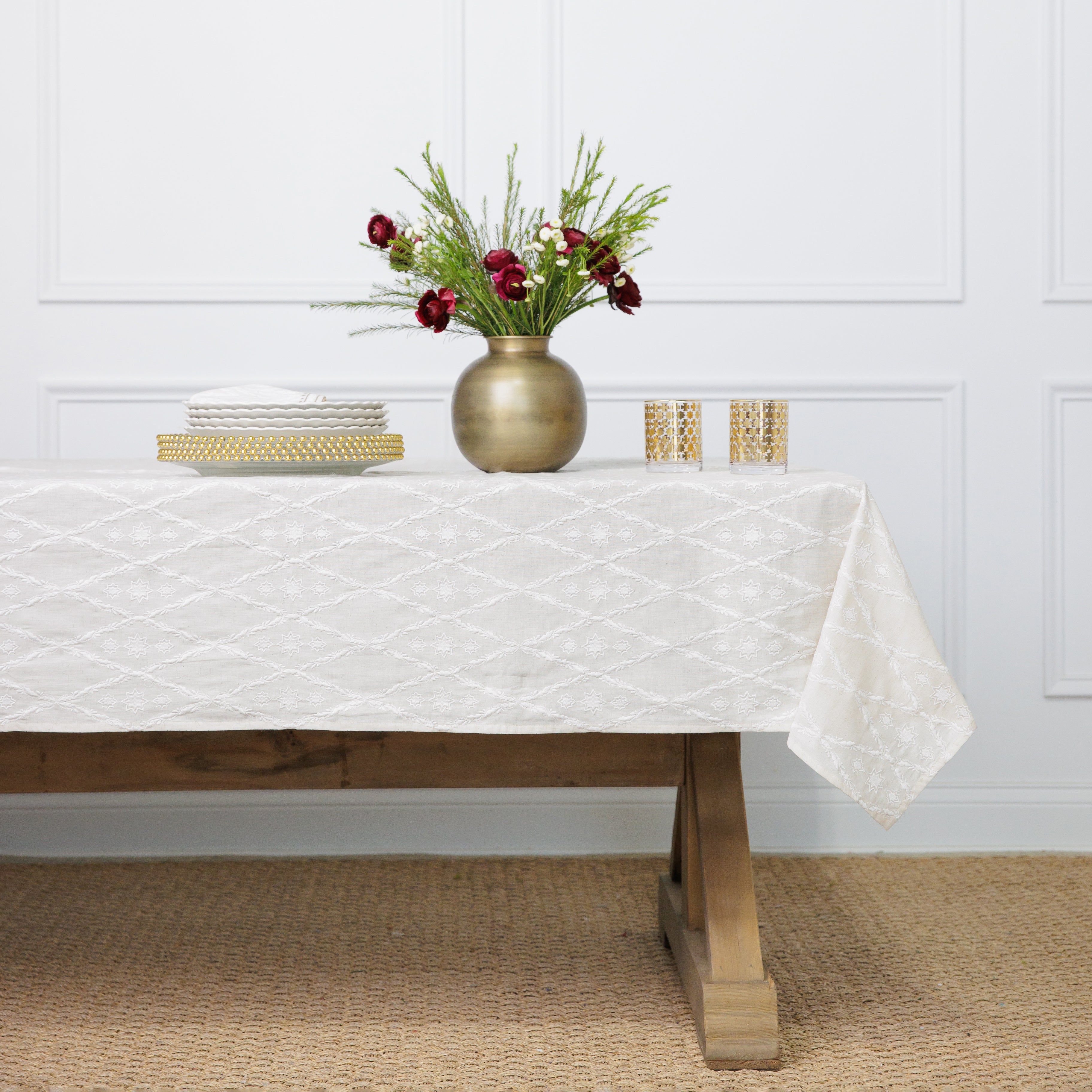 An ivory tablecloth with an embroidered diamond pattern on a white background