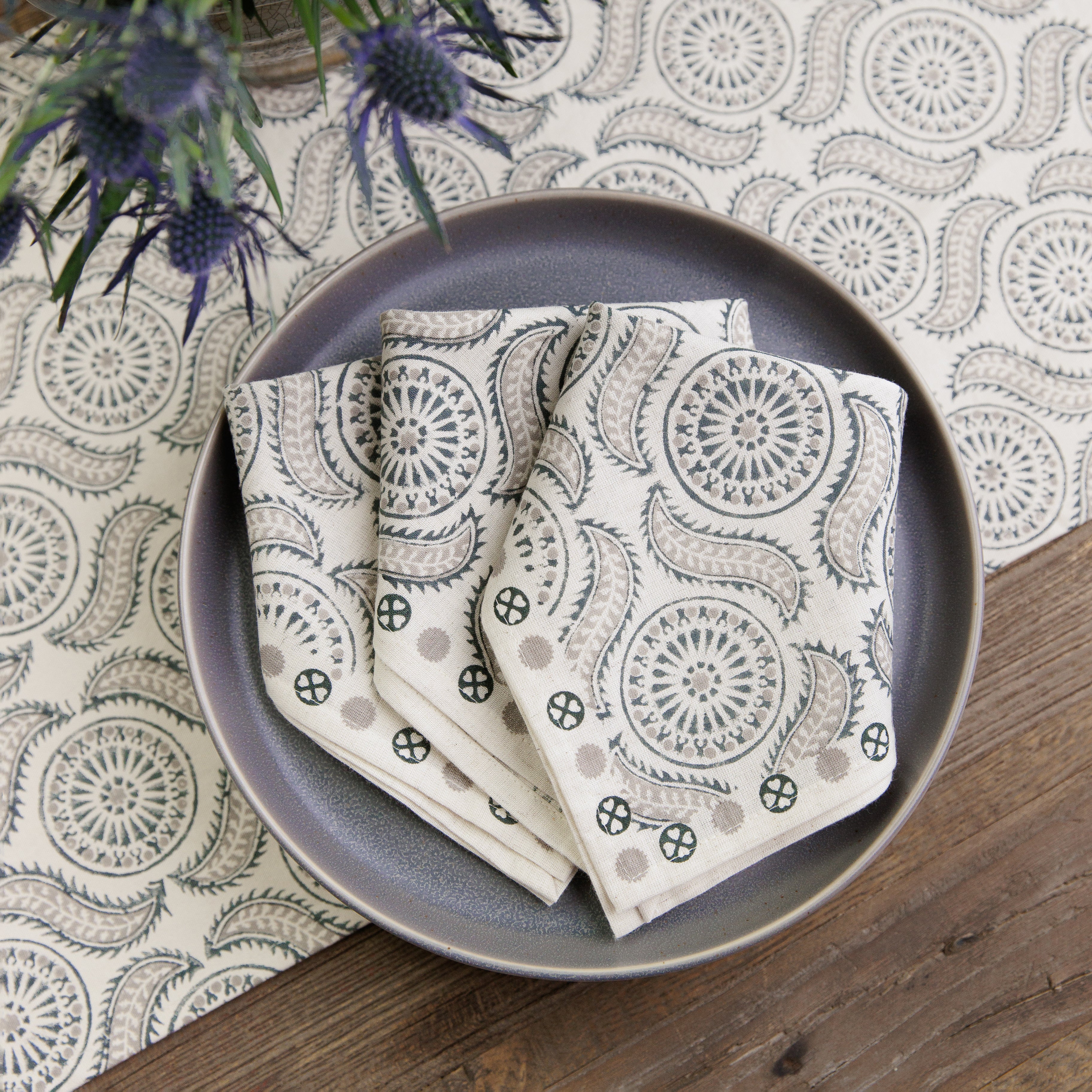 A set of folded cloth napkins with a geometric pattern, displayed on a table with other tableware.