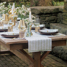 A hunter green table runner with a palm tree pattern displayed on a table set for dining.