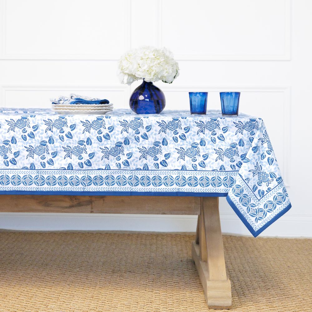 Tablecloth with blue floral pattern on a wooden table against a white wall.