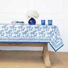Tablecloth with blue floral pattern on a wooden table against a white wall.