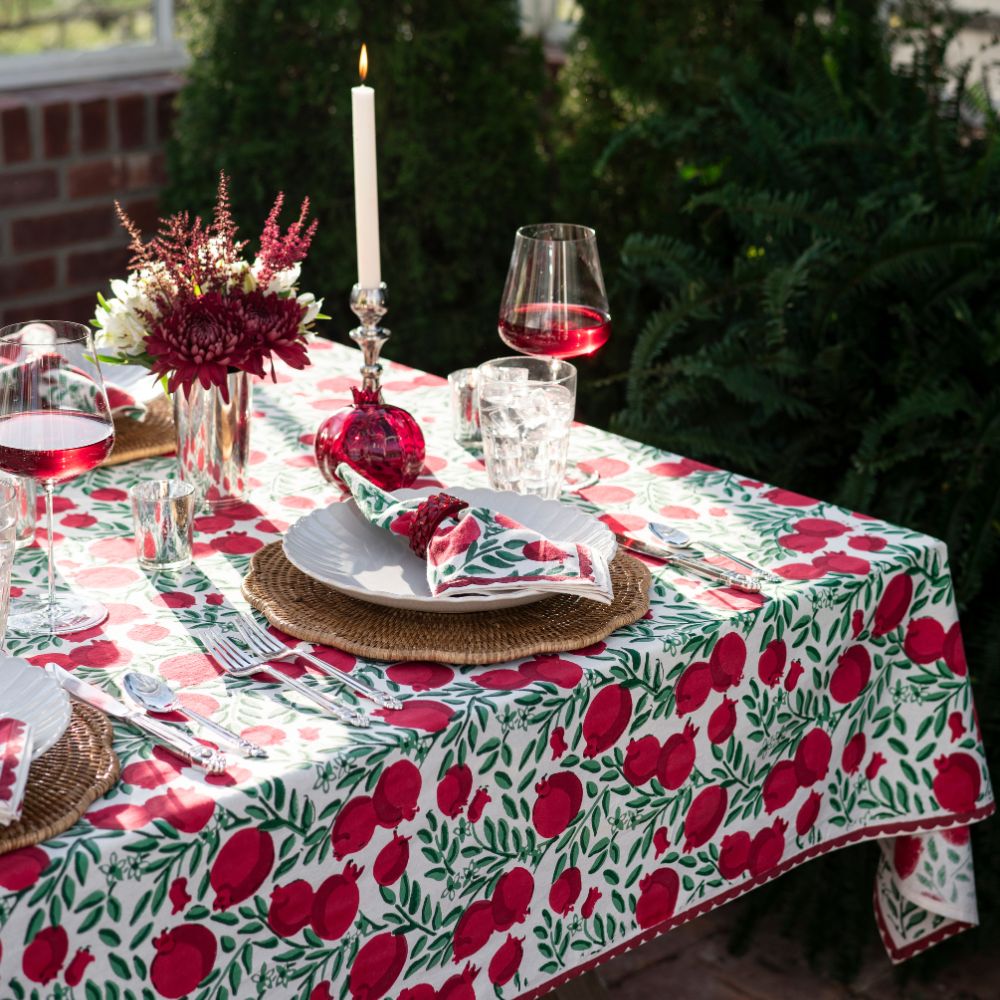 A table setting featuring pomegranate napkins and a tablecloth.
