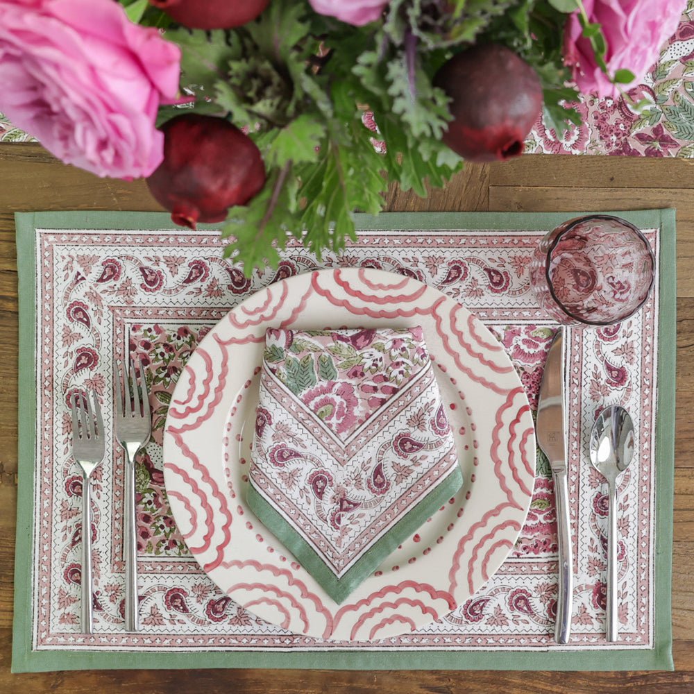 Table setting with patterned placemat, plate, and napkin on a wooden table.