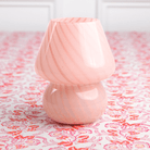 A pink lamp with a conical shade placed on a patterned surface.
