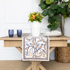 Decorative table setting with a floral arrangement, plates, and a decorative towel on a wooden table.