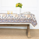 Tablecloth with floral pattern on a wooden table against a white wall.