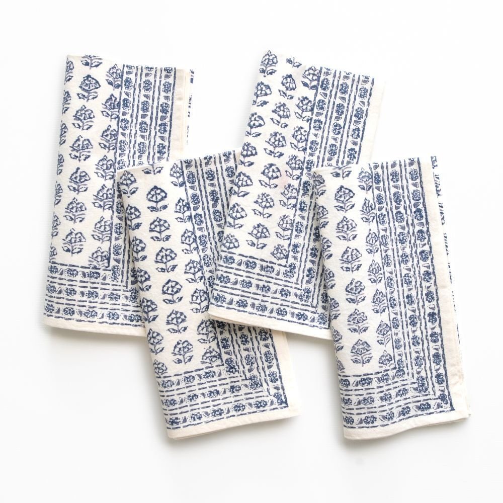Set of three folded white napkins with blue floral patterns on a white background