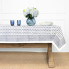 Tablecloth with floral pattern on a wooden table against a white wall.