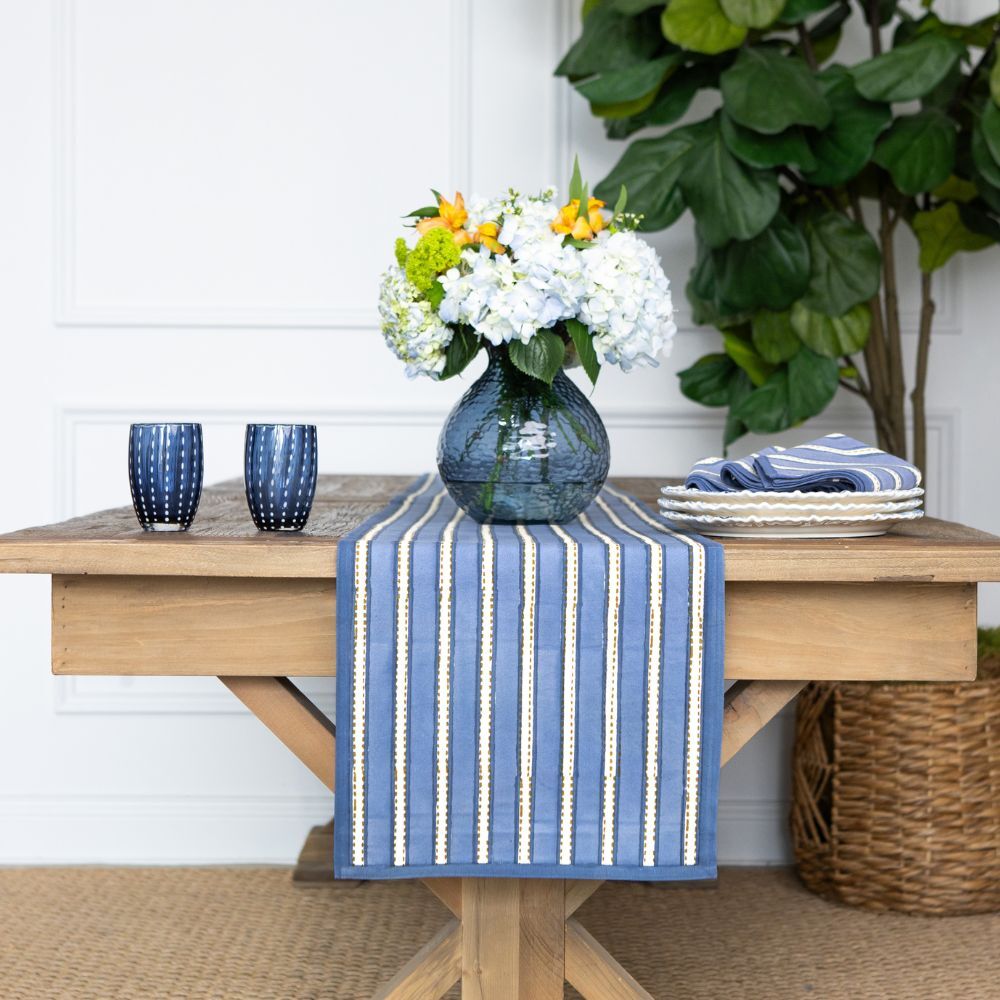 Wooden table with a blue striped runner and decorative accents