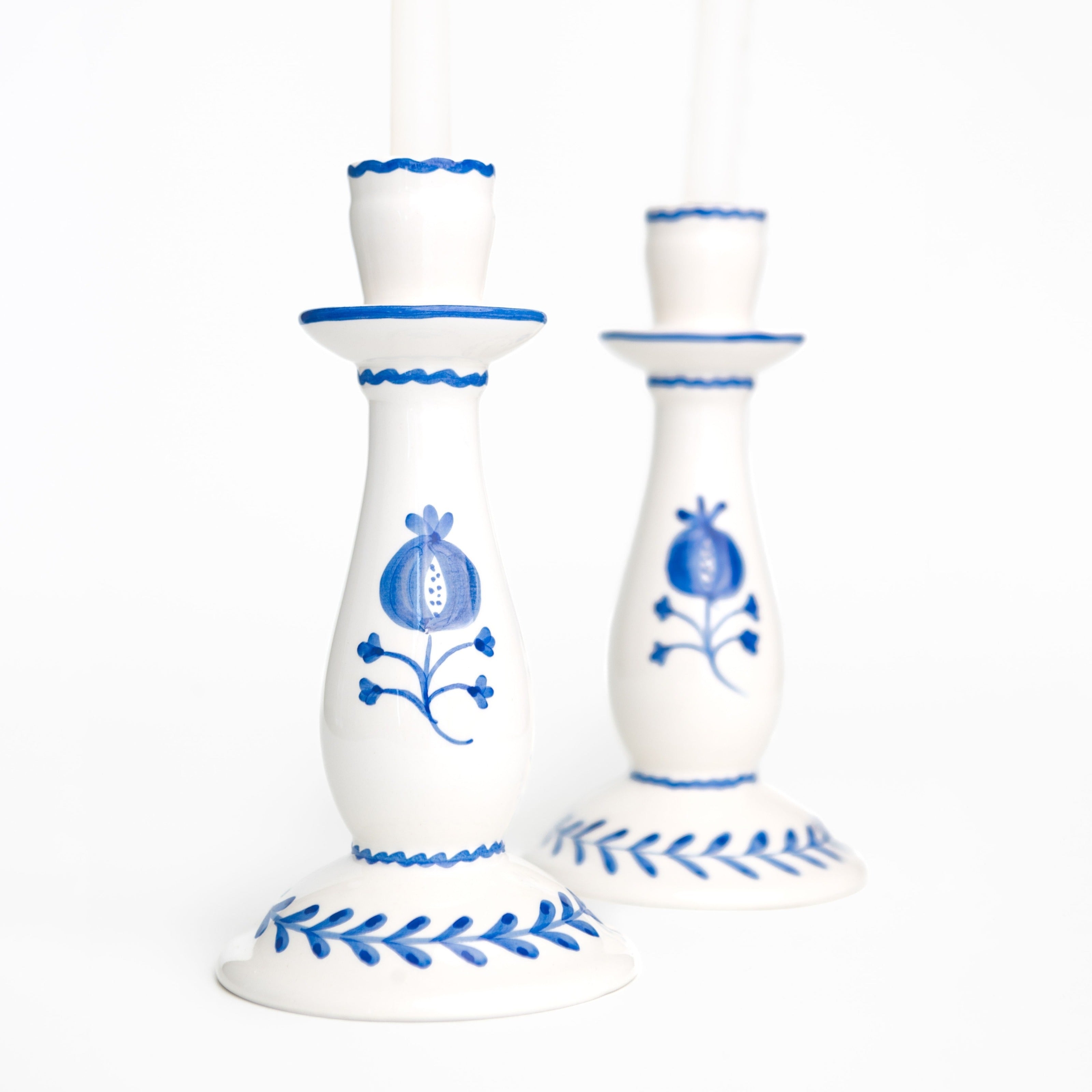 White candle holders with cobalt blue floral designs on a white background