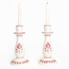 Pair of white candlesticks with red floral patterns on a white background