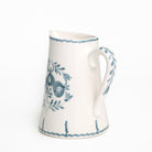 White ceramic pitcher with blue floral patterns on a white background