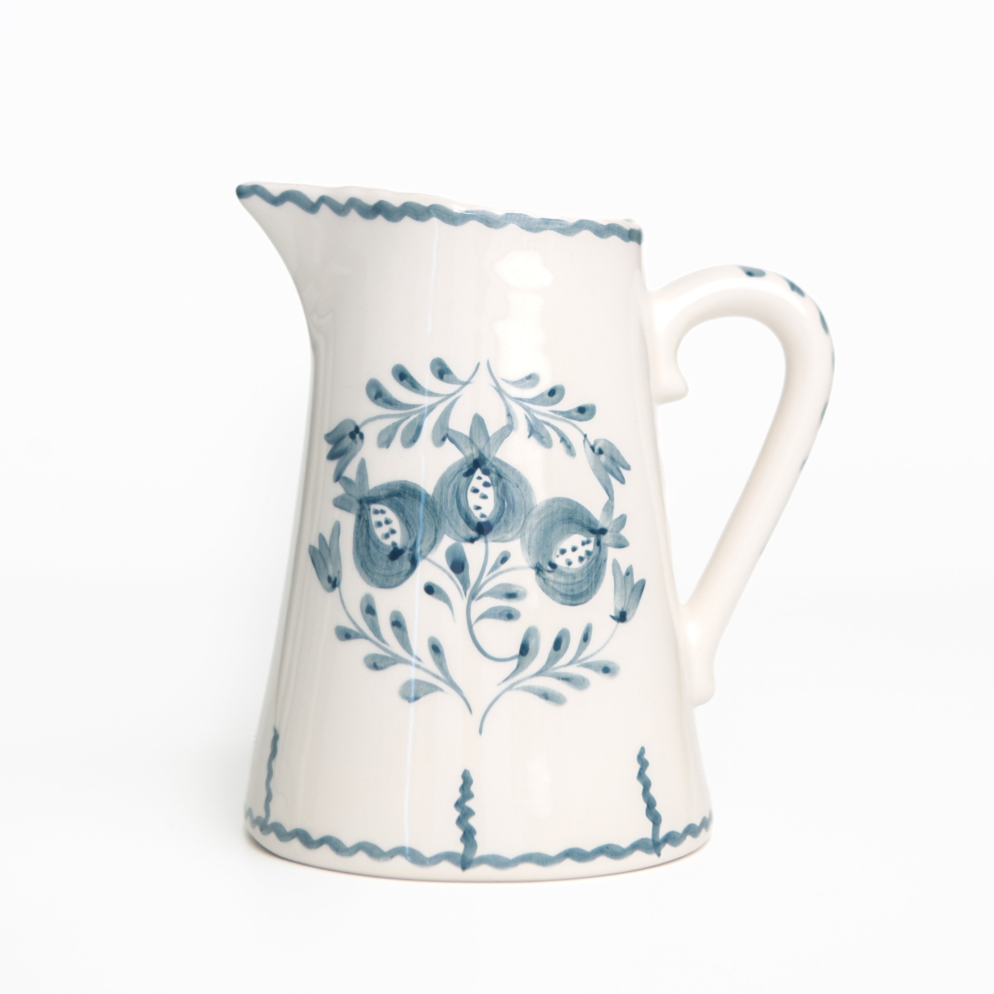 White ceramic pitcher with blue floral patterns on a white background