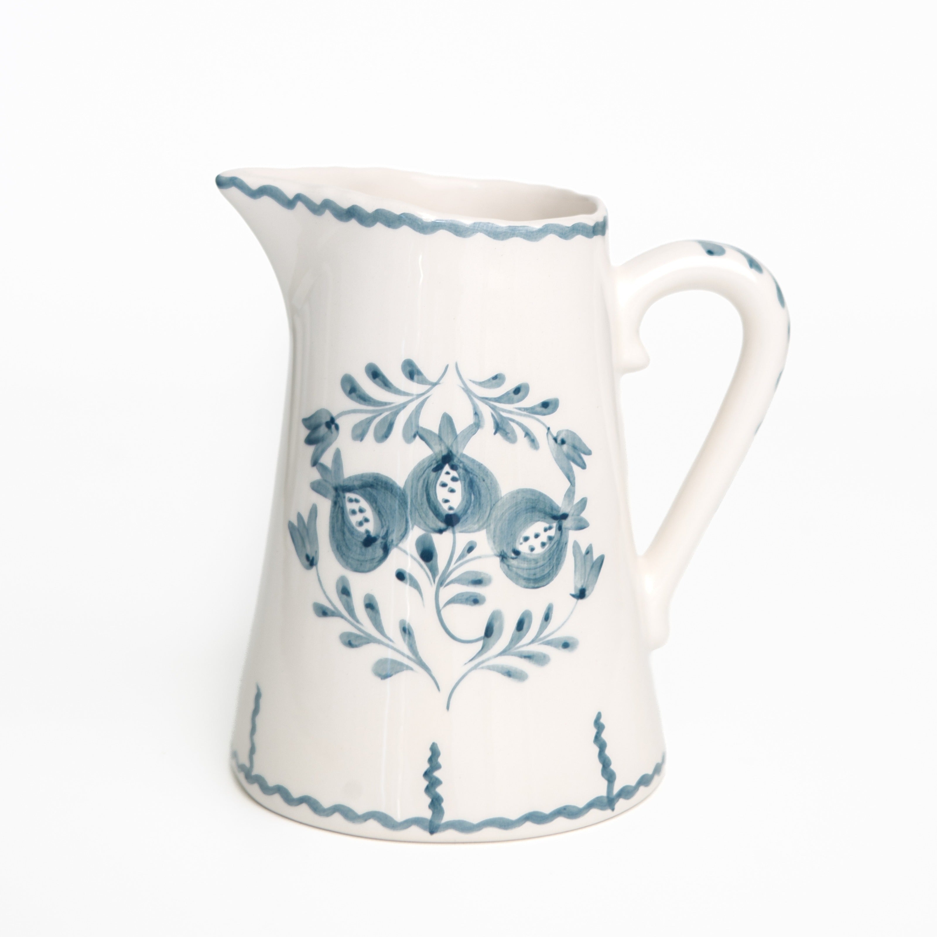 White ceramic pitcher with blue floral patterns on a white background