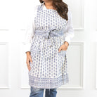 Woman wearing a white apron with a blue floral pattern against a white background