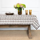 Tablecloth with decorative pattern on a wooden table with flowers and candles.
