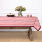 Table with a red and white striped tablecloth, flowers, and candles in a room.