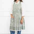 Person wearing a green and white patterned apron over a white shirt and blue jeans on a white background