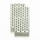 Folded tea towels with green leaf pattern on a white background