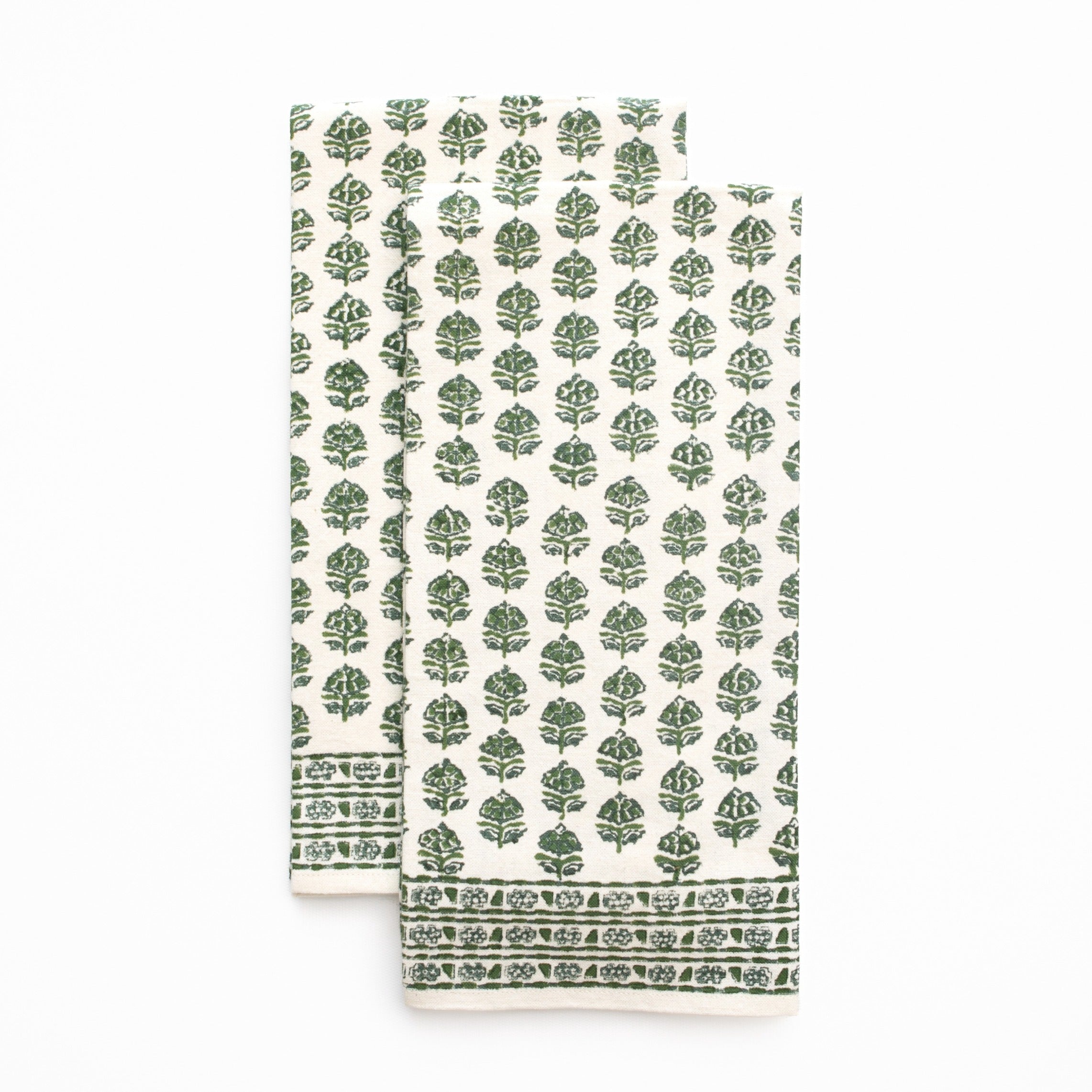Folded tea towels with green leaf pattern on a white background