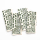 Set of four green and white patterned napkins on a white background