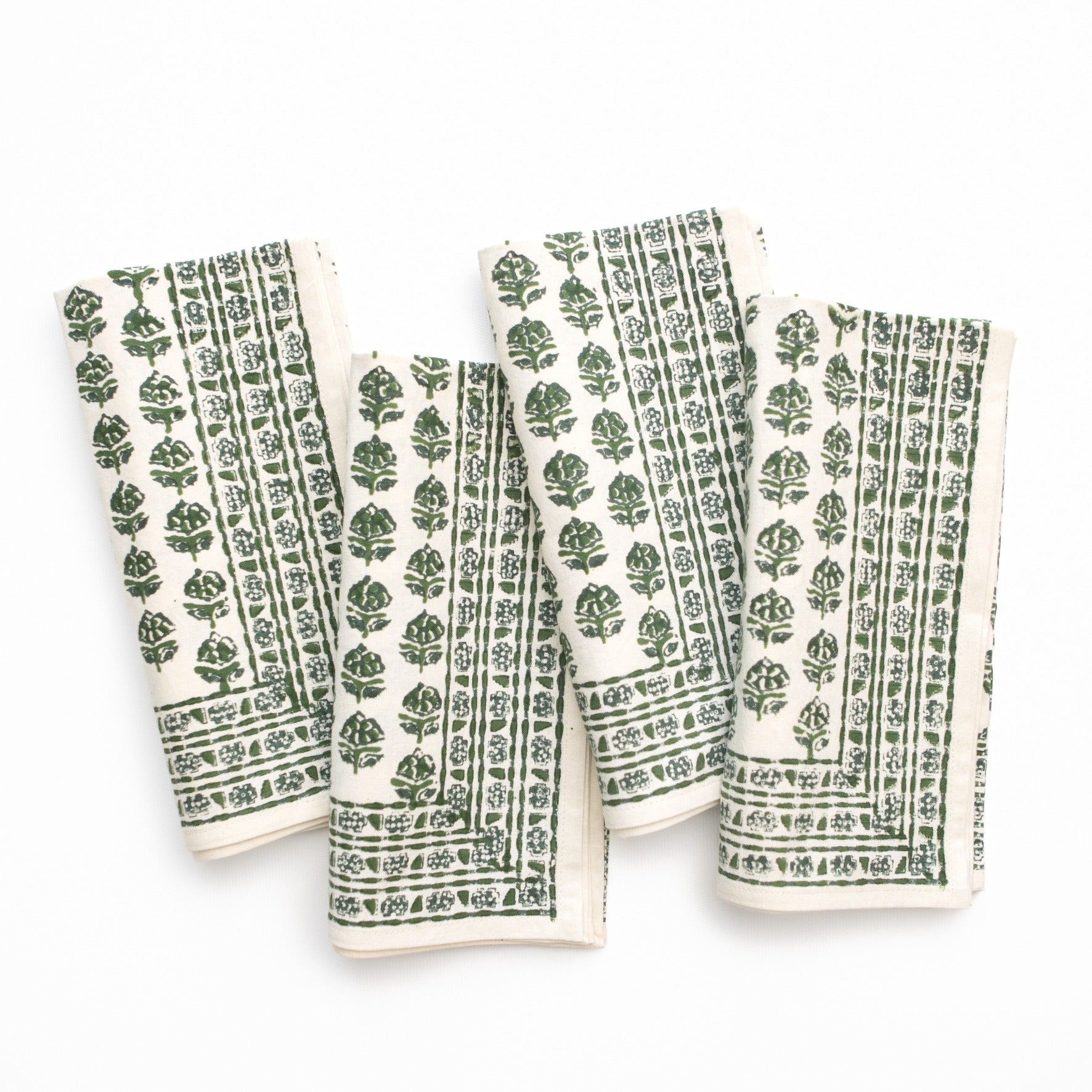 Set of four green and white patterned napkins on a white background