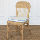 Wicker chair with a patterned cushion on a textured floor.