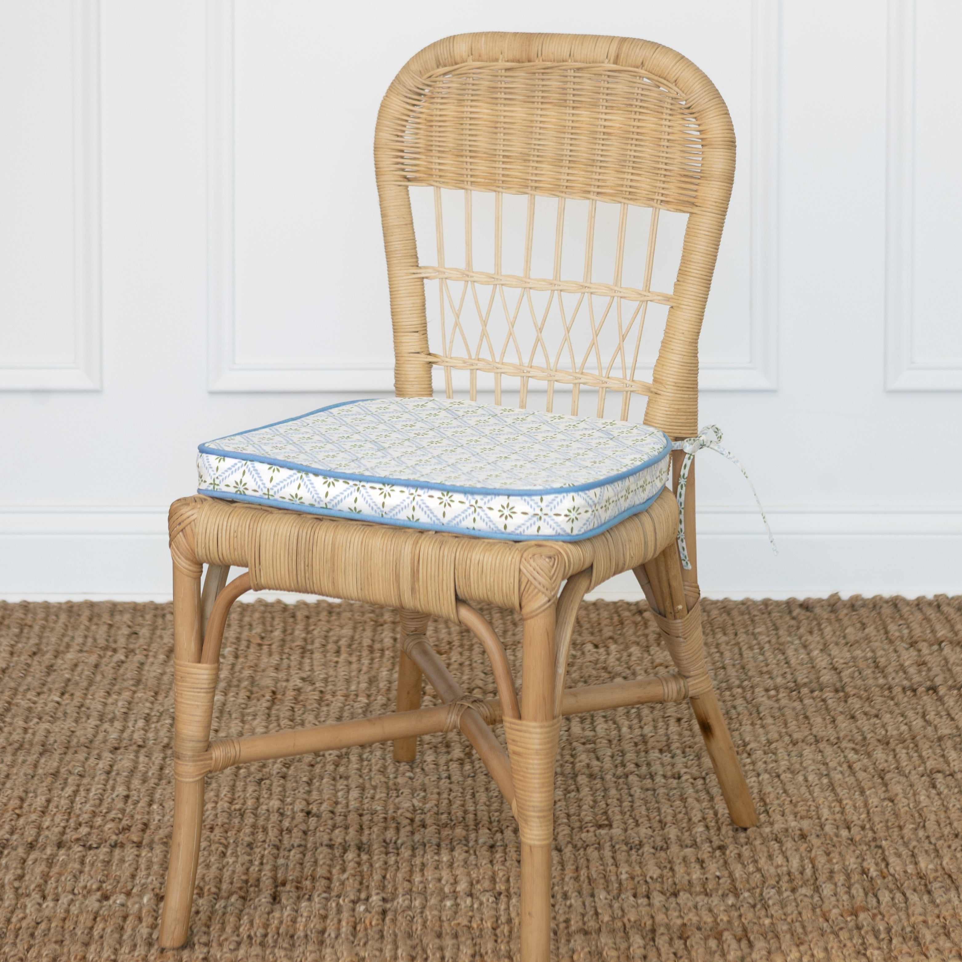 Wicker chair with a patterned cushion on a textured floor.