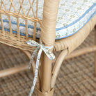 Close-up of a wicker chair with a decorative ribbon and cushioned seat.