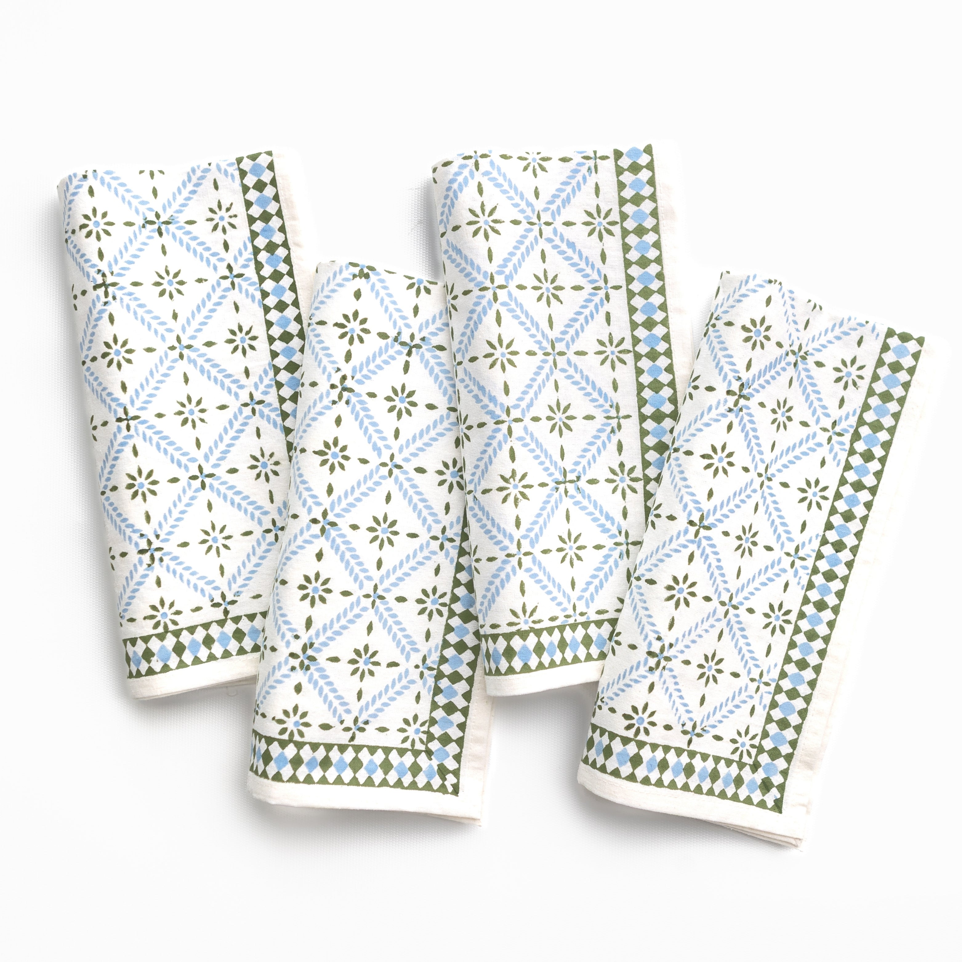 Four patterned napkins with green and blue designs on a white background