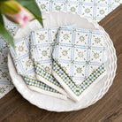 Stack of patterned napkins on a white plate with a wooden surface and floral background