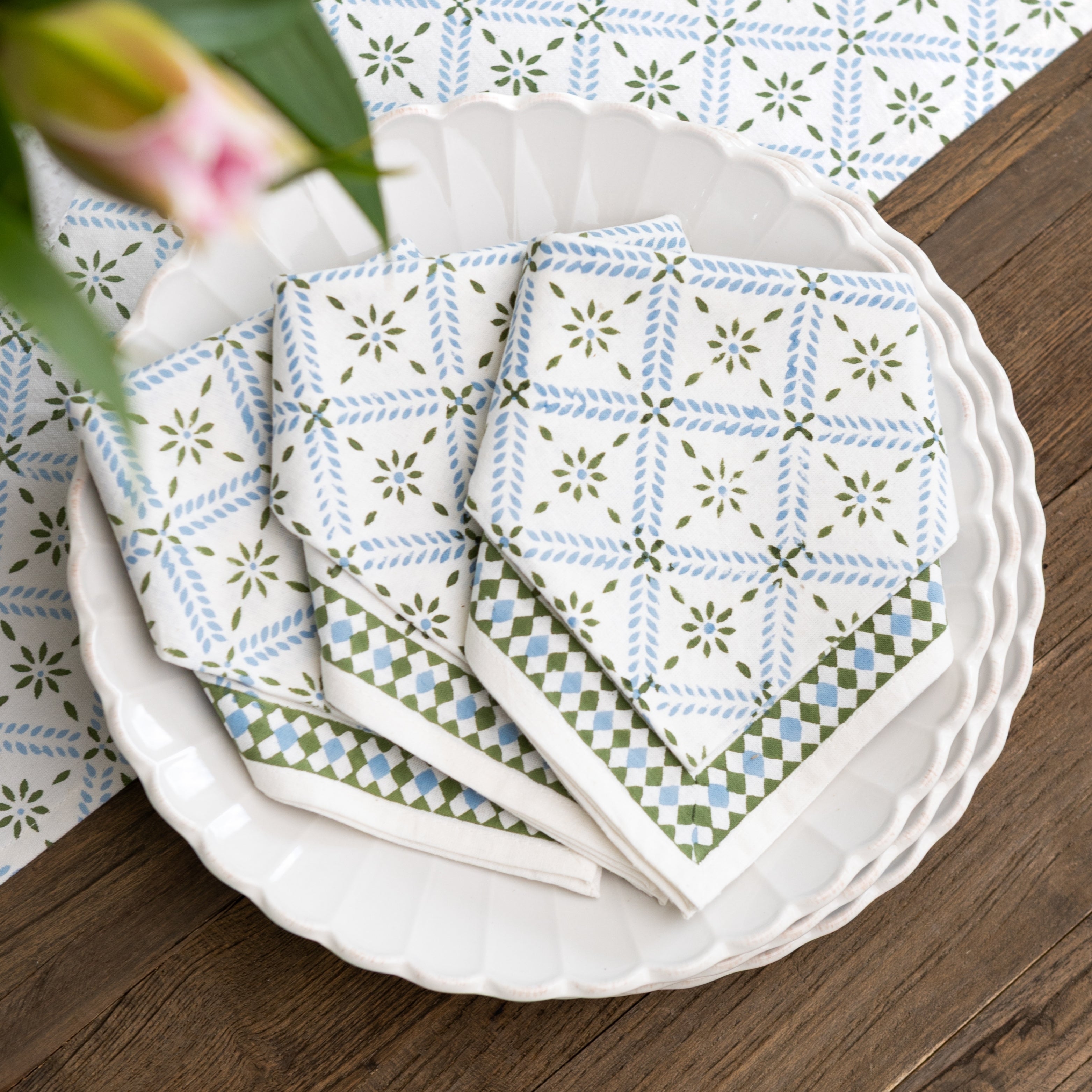 Stack of patterned napkins on a white plate with a wooden surface and floral background