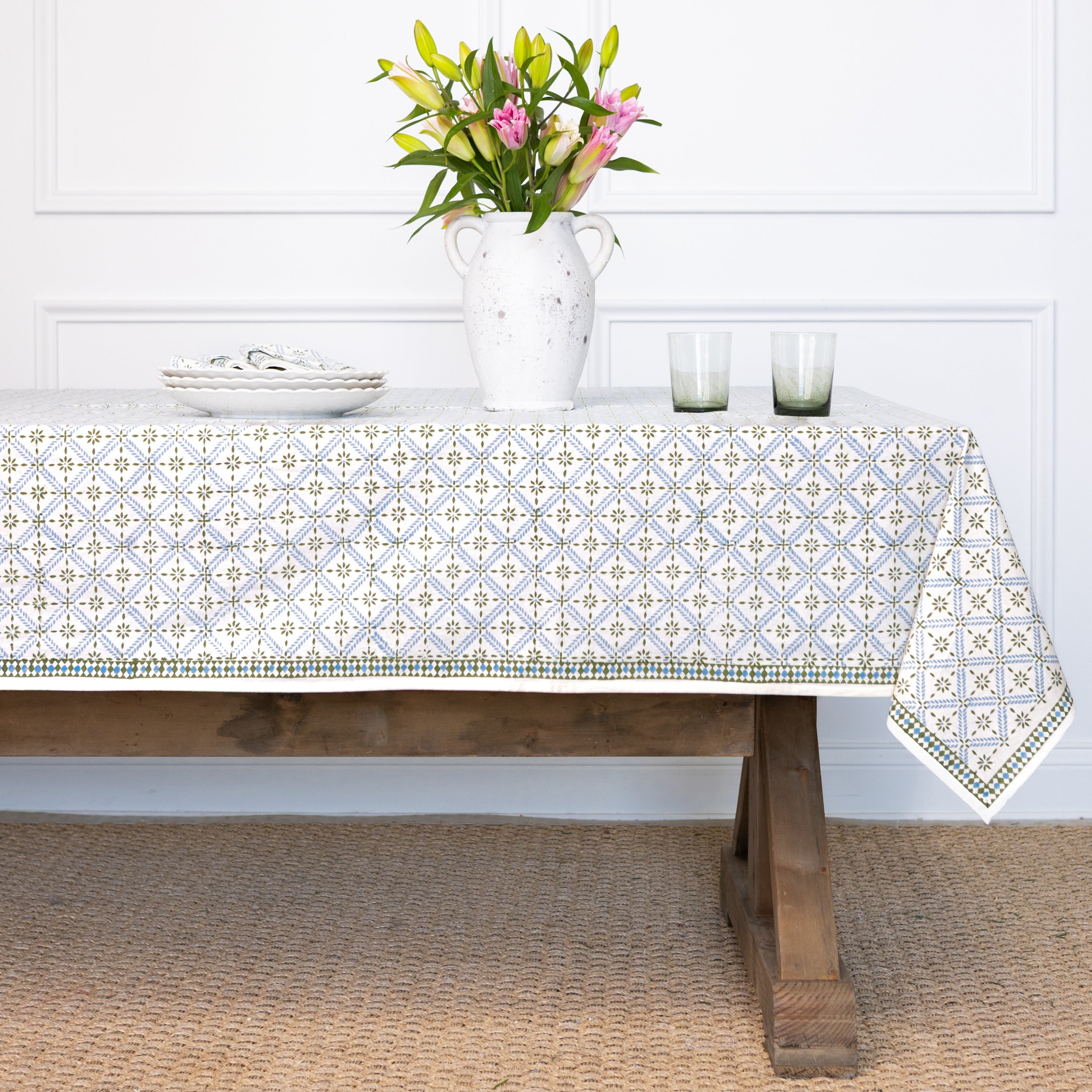 Tablecloth with geometric pattern on a wooden table, white wall background