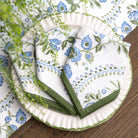 Set of floral-patterned napkins with green borders on a wooden surface