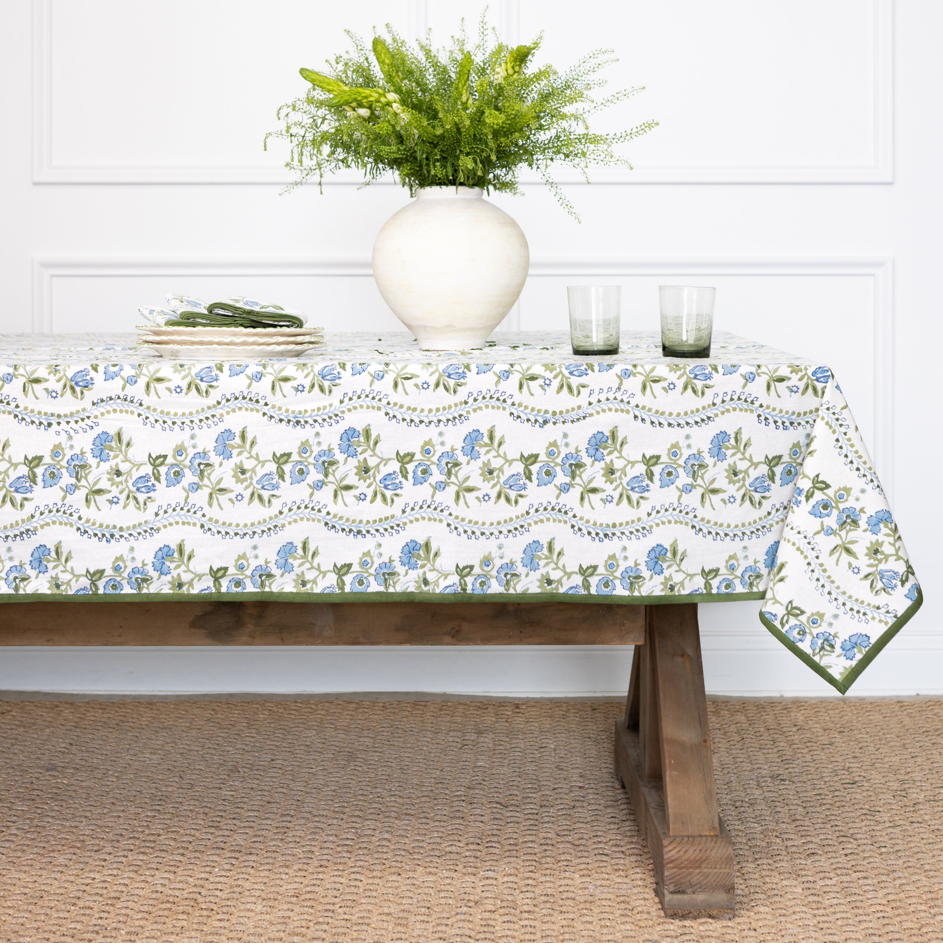 Tablecloth with floral pattern on a wooden table, white wall background