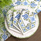 Stack of patterned plates and napkins on a decorative tablecloth.