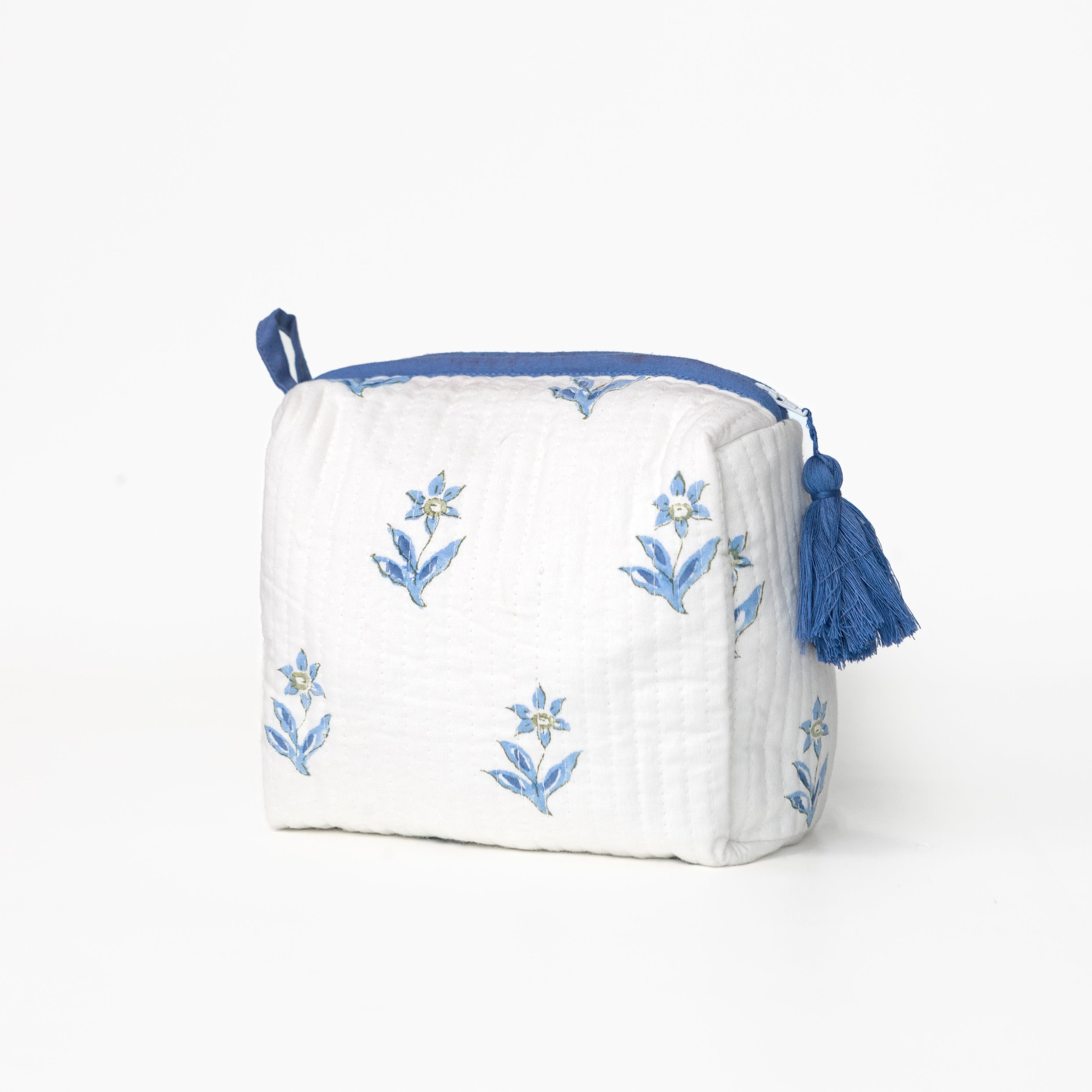 White pouch with blue floral embroidery and tassels on a white background