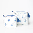 Two white pouches with blue floral patterns and tassels on a white background
