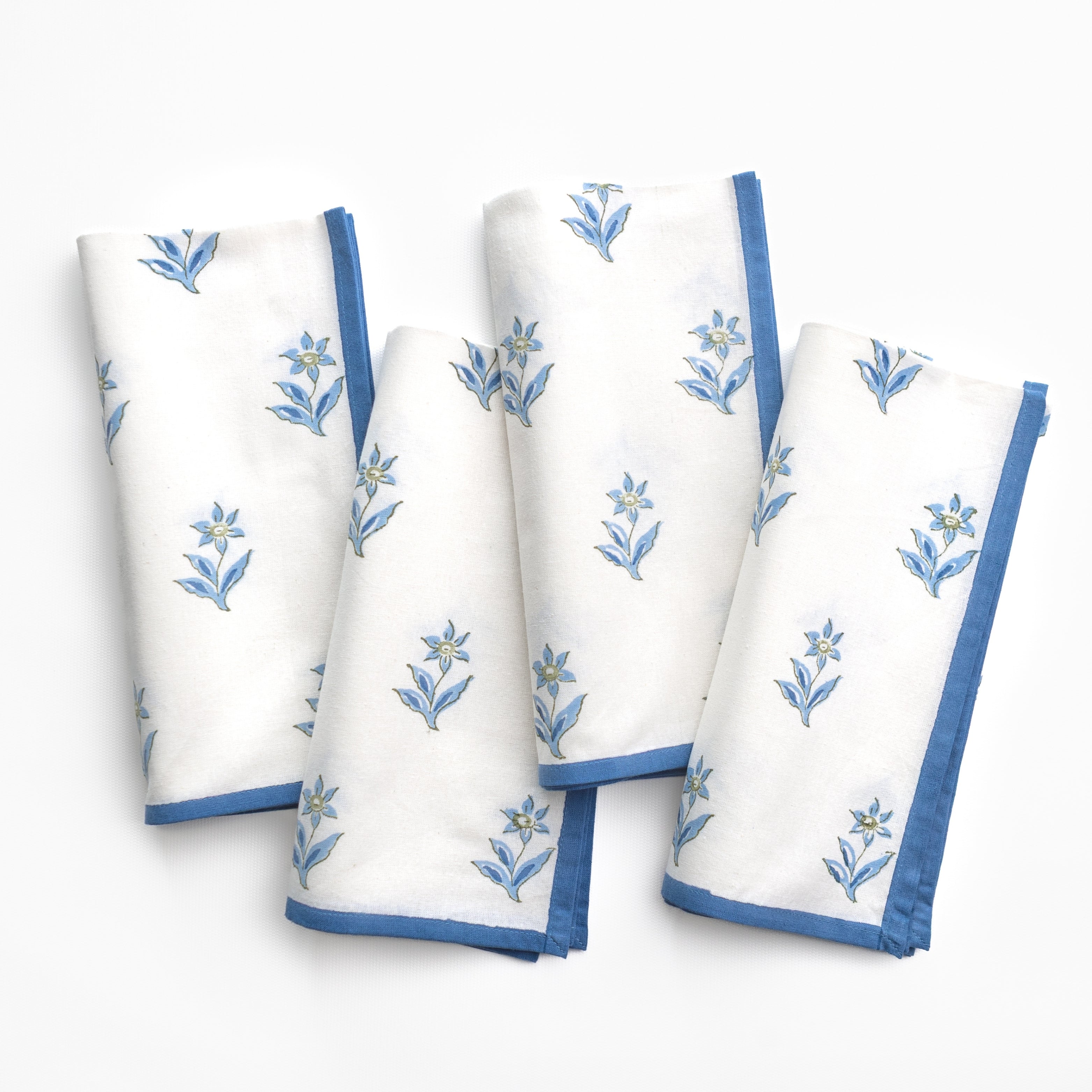 Set of white napkins with blue floral embroidery on a white background