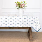 Tablecloth with blue floral pattern on a wooden table with a vase of flowers.
