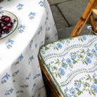 Floral-patterned tablecloth and chair pad on a bamboo chair.