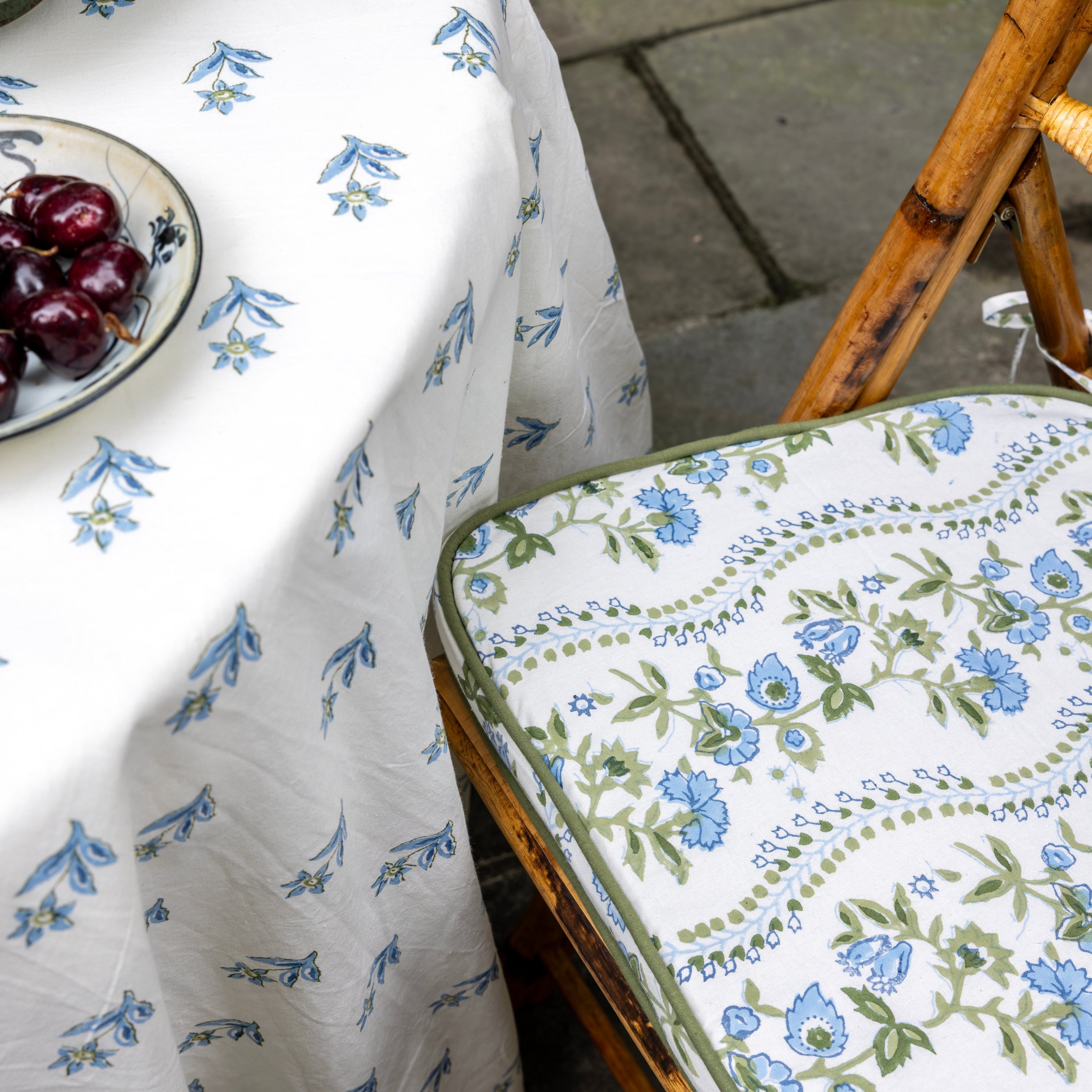Floral-patterned tablecloth and chair pad on a bamboo chair.