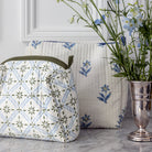 Patterned bag and pillow on a marble surface with a vase of flowers.