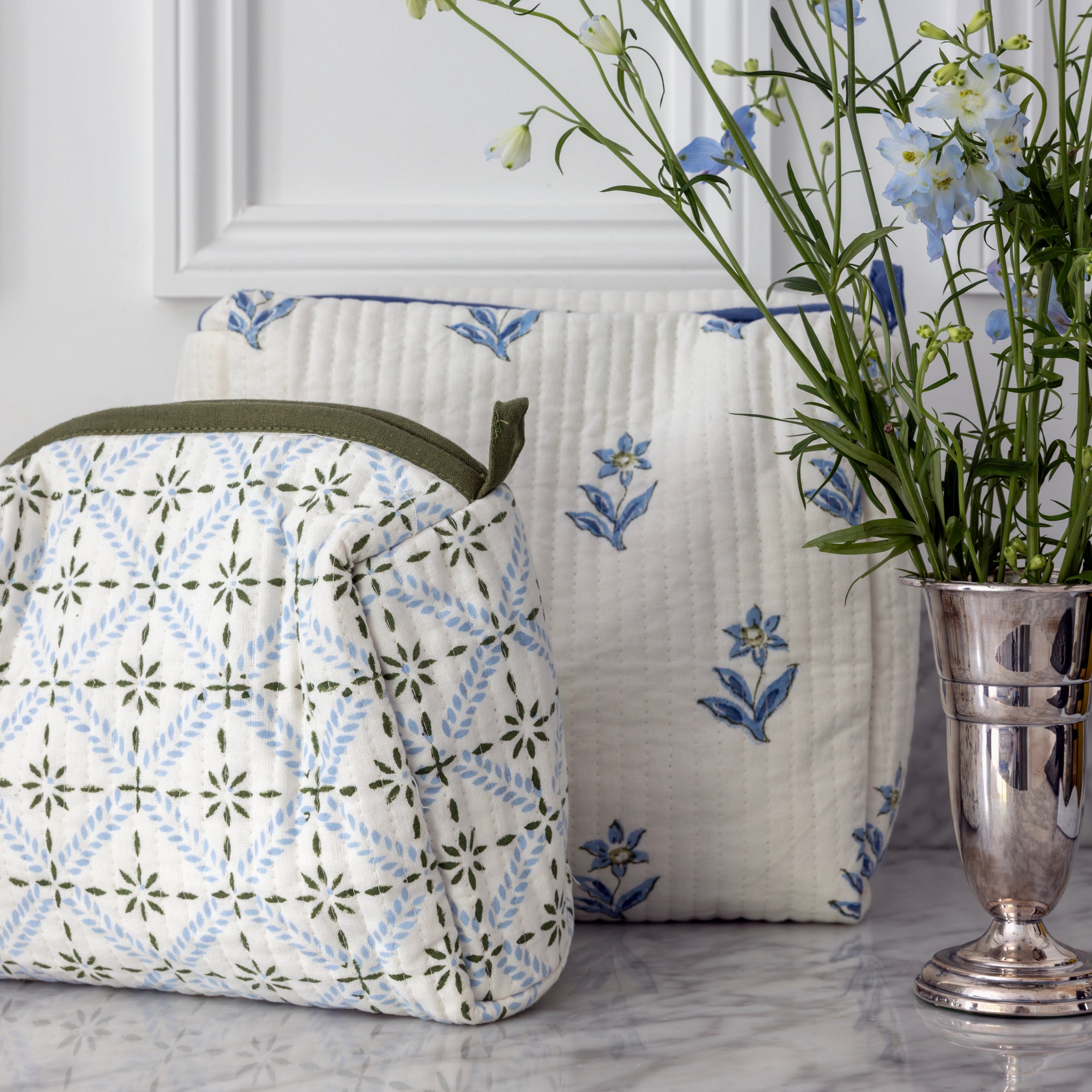 Patterned bag and pillow on a marble surface with a vase of flowers.