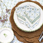 Plated dish with a patterned napkin on a woven placemat, surrounded by decorative elements.