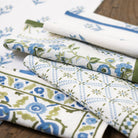 Stack of floral and geometric patterned fabric swatches on a wooden surface